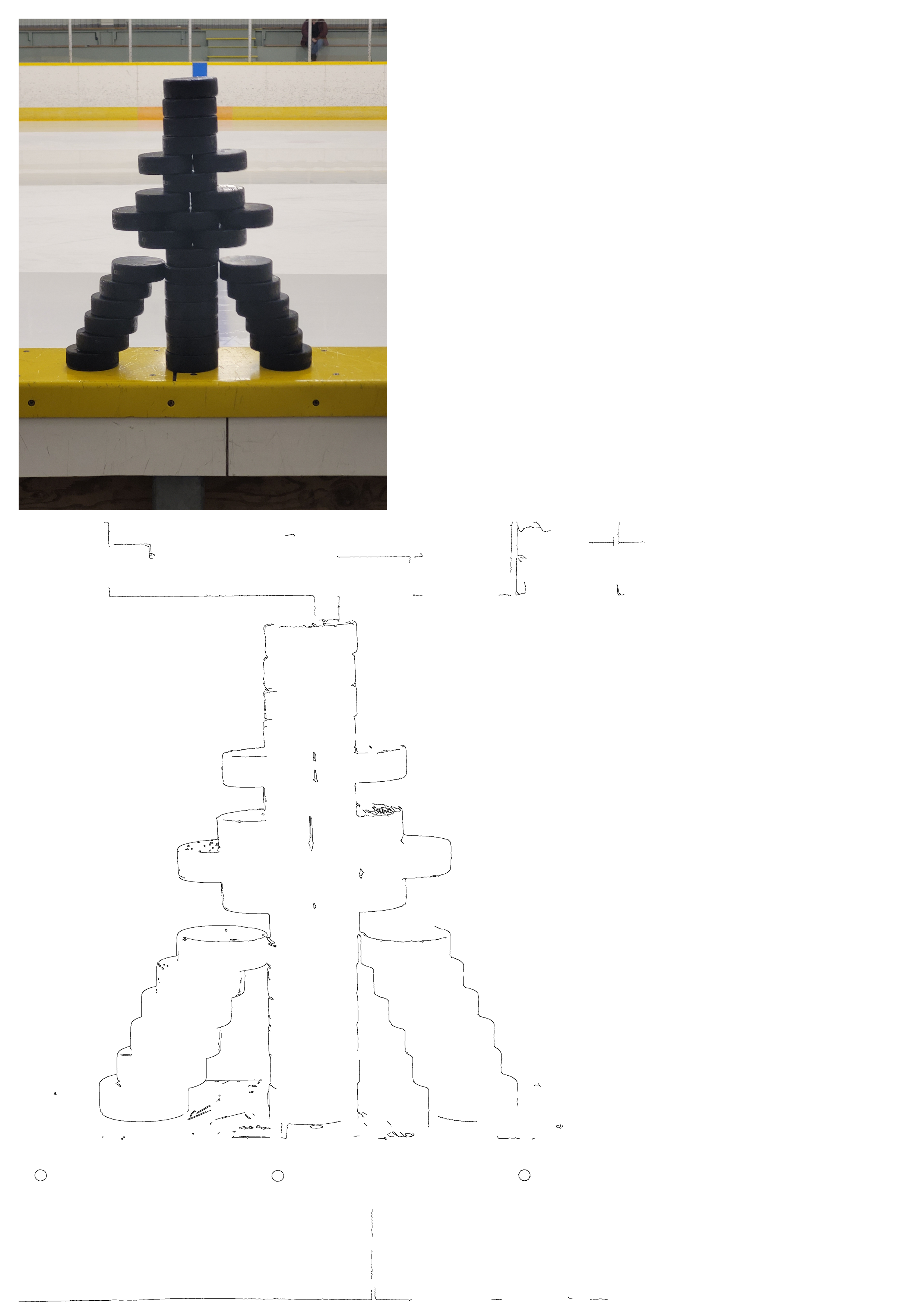 A creative tower made of stacked black hockey pucks, prominently displayed on the yellow barrier of an ice rink. The icy surface is visible.